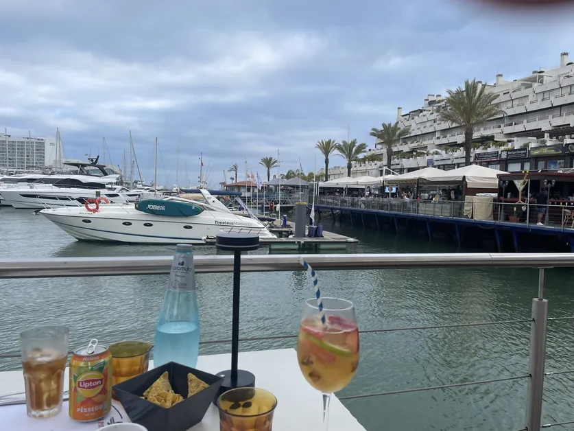 Photo of a cocktail with a marina in the background begs the question: can you collect Social Security while living the good life abroad?